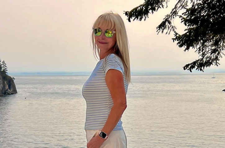 woman standing in front of an ocean with a smile on her face