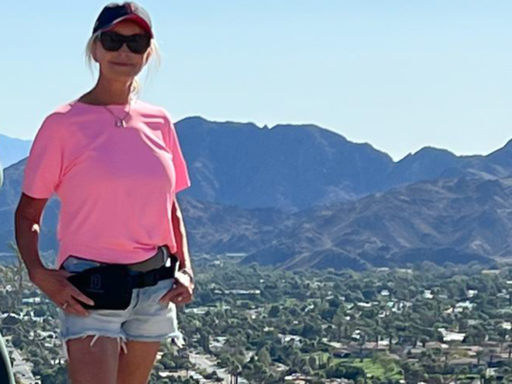 mature woman standing triumphantly on top of a mountain peak at sunrise