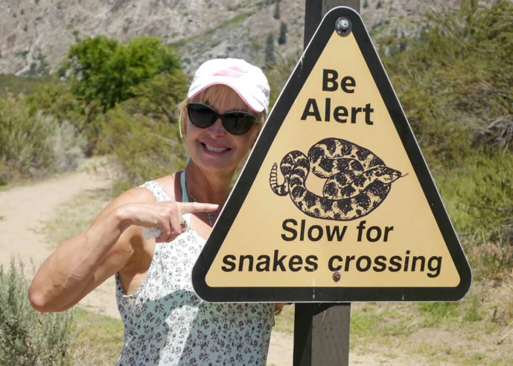 happy woman pointing at a snake crossing sign