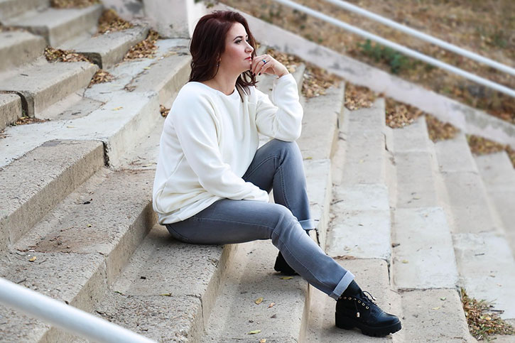 A mature woman sitting on the steps, deep in thought.