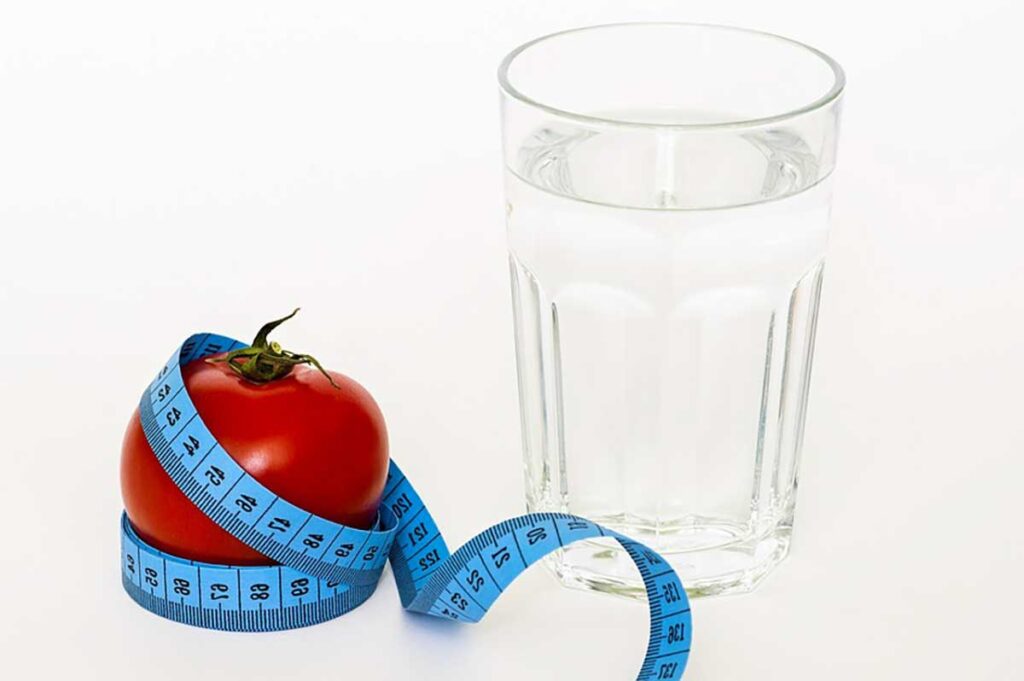 apple with measuring tape around it and glass of water