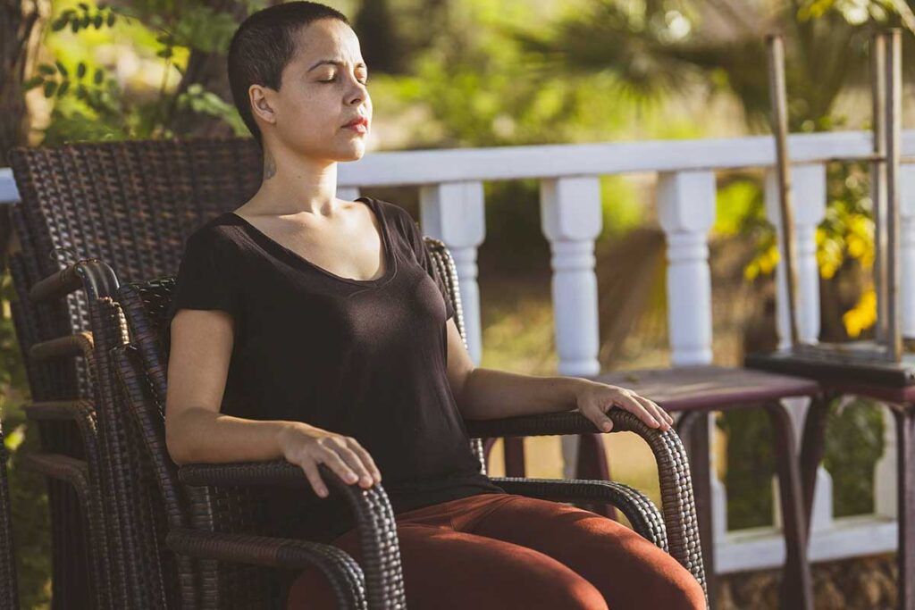Senior woman seated in a chair, lost in thought with a calm expression.